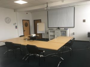 Professional meeting room with presentation screen, projector, and client seating. Creating first impressions that last.