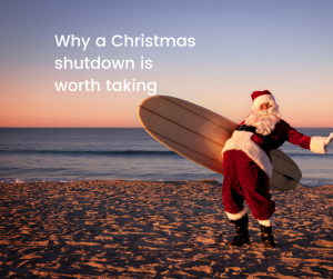 santa on a beach with a surfboard takling a well earned break and showing us why a christmas shutdown is worth taking
