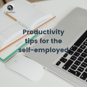 a white desk with a keyboard and a planner opened out showing productivity tips ofr the self-employed